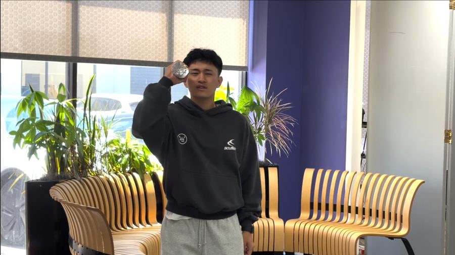 The creator raising a flashlight beside his face in an office.